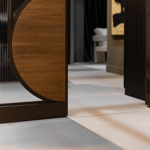 Luxe bronskleurige stalen deur met boogvormig ribbelglas en geribbeld houten zijpaneel.