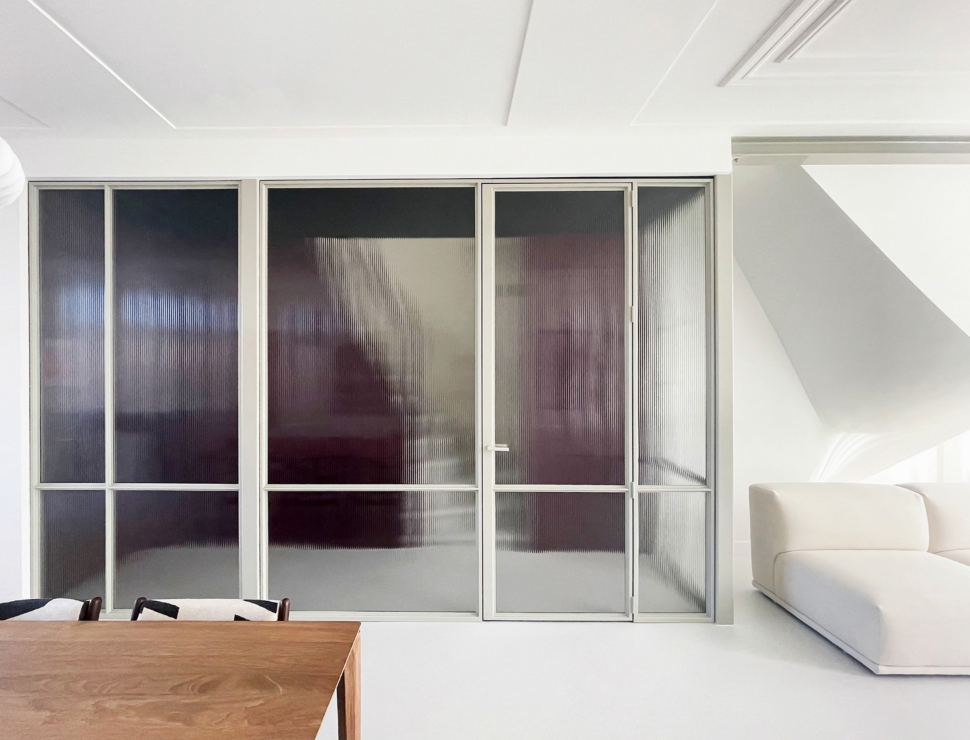 Witte stalen deur met geribbeld glas als stijlvolle roomdivider in een modern interieur.