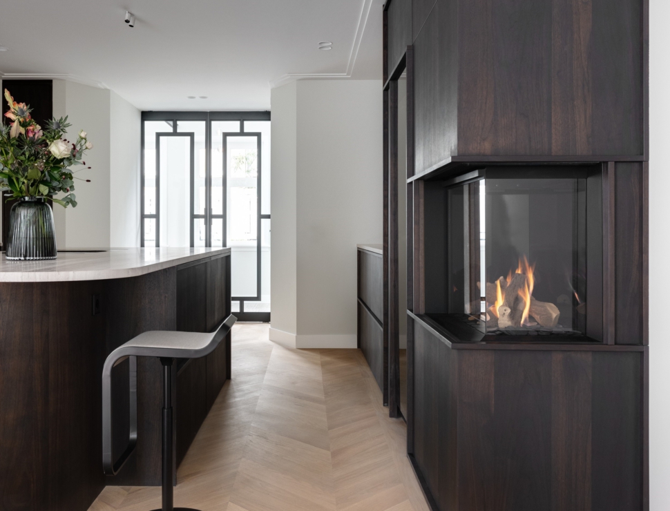 Zwarte stalen taatsdeuren met glas als stijlvolle afscheiding in een luxe keuken met haard.
