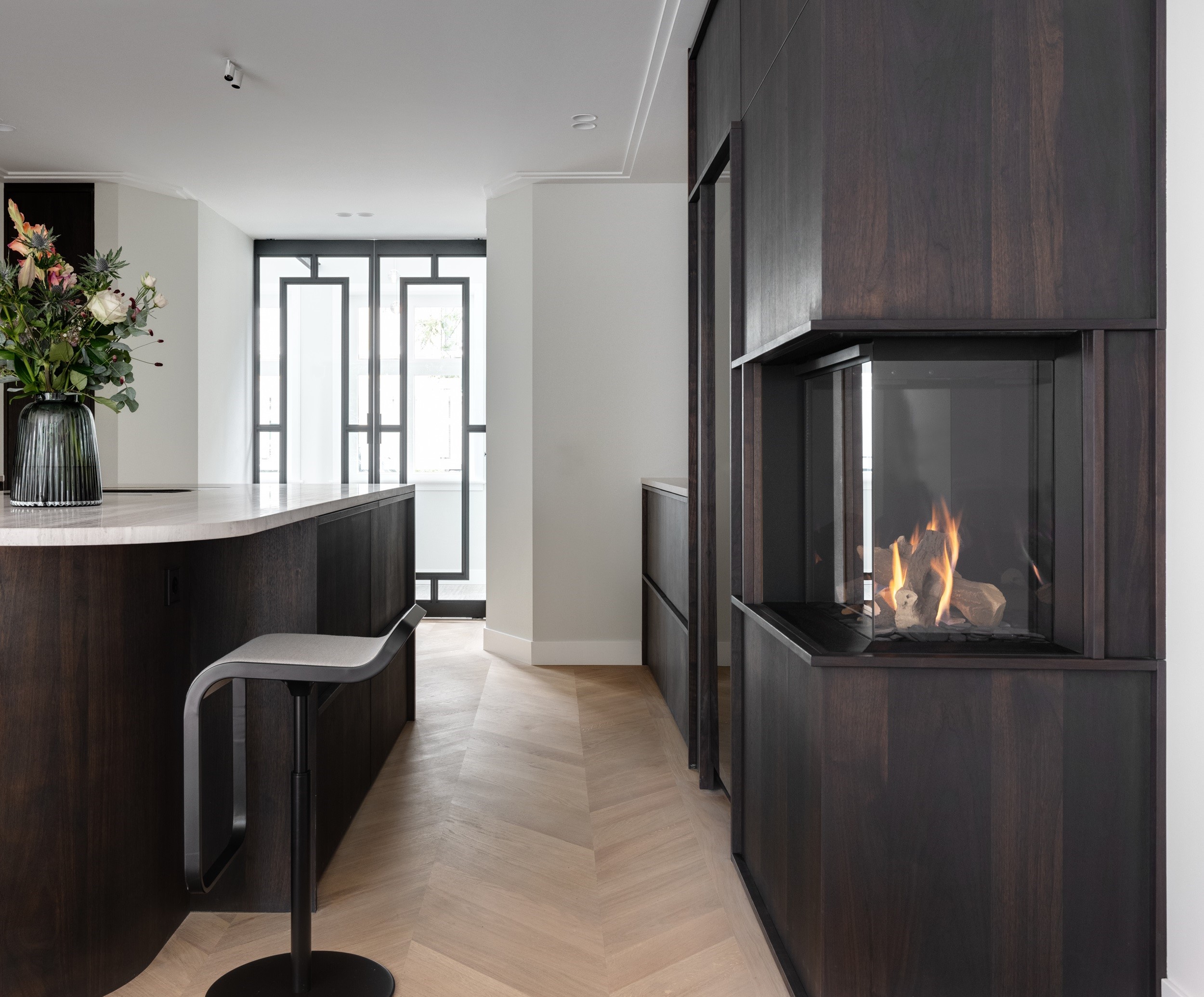 Zwarte stalen taatsdeuren met glas als stijlvolle afscheiding in een luxe keuken met haard.