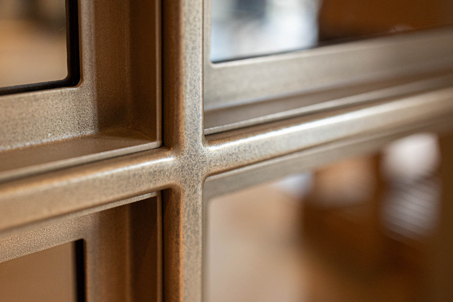 Detail van bronzen stalen deurprofiel met glas en verfijnde afwerking.