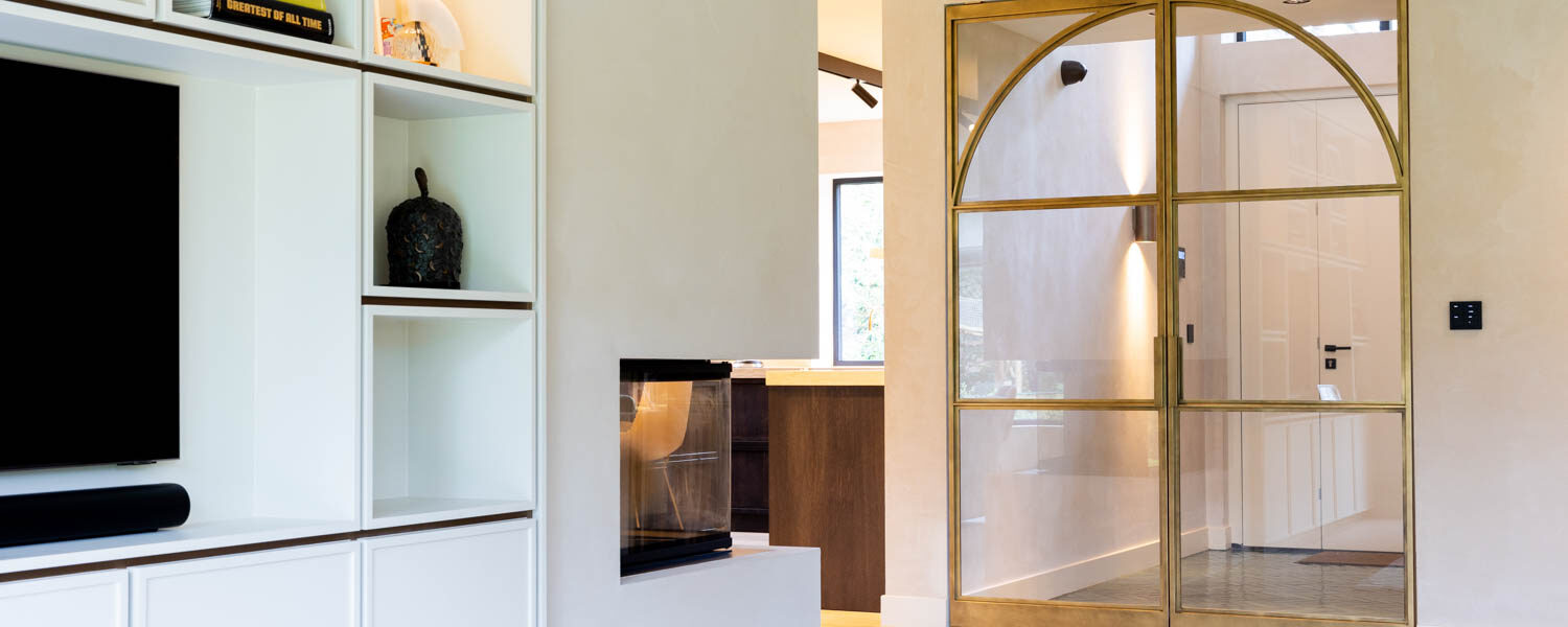 Gesloten messing stalen deuren met gebogen glasdetails in een stijlvolle woning.