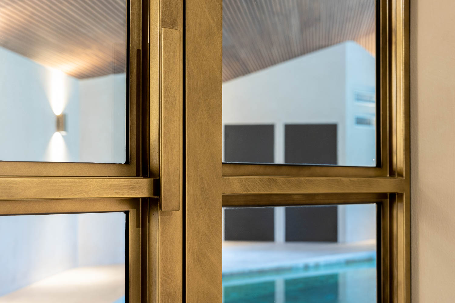 Luxe messing stalen deuren met glas, doorkijk naar overdekt zwembad.