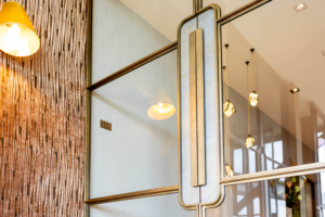 Luxe messing stalen deur met glas en elegante verticale handgreep in modern interieur.