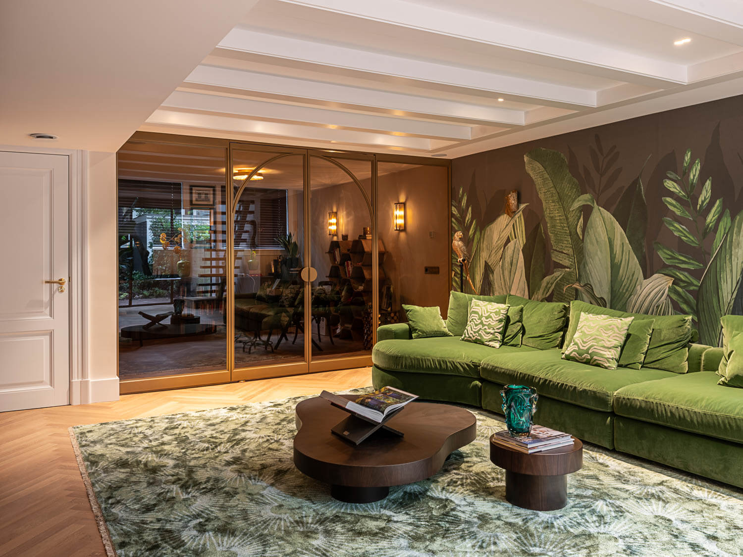 Luxe bronzen stalen deuren met glas en een elegant boogdesign, als roomdivider in een stijlvol interieur met groene accenten.