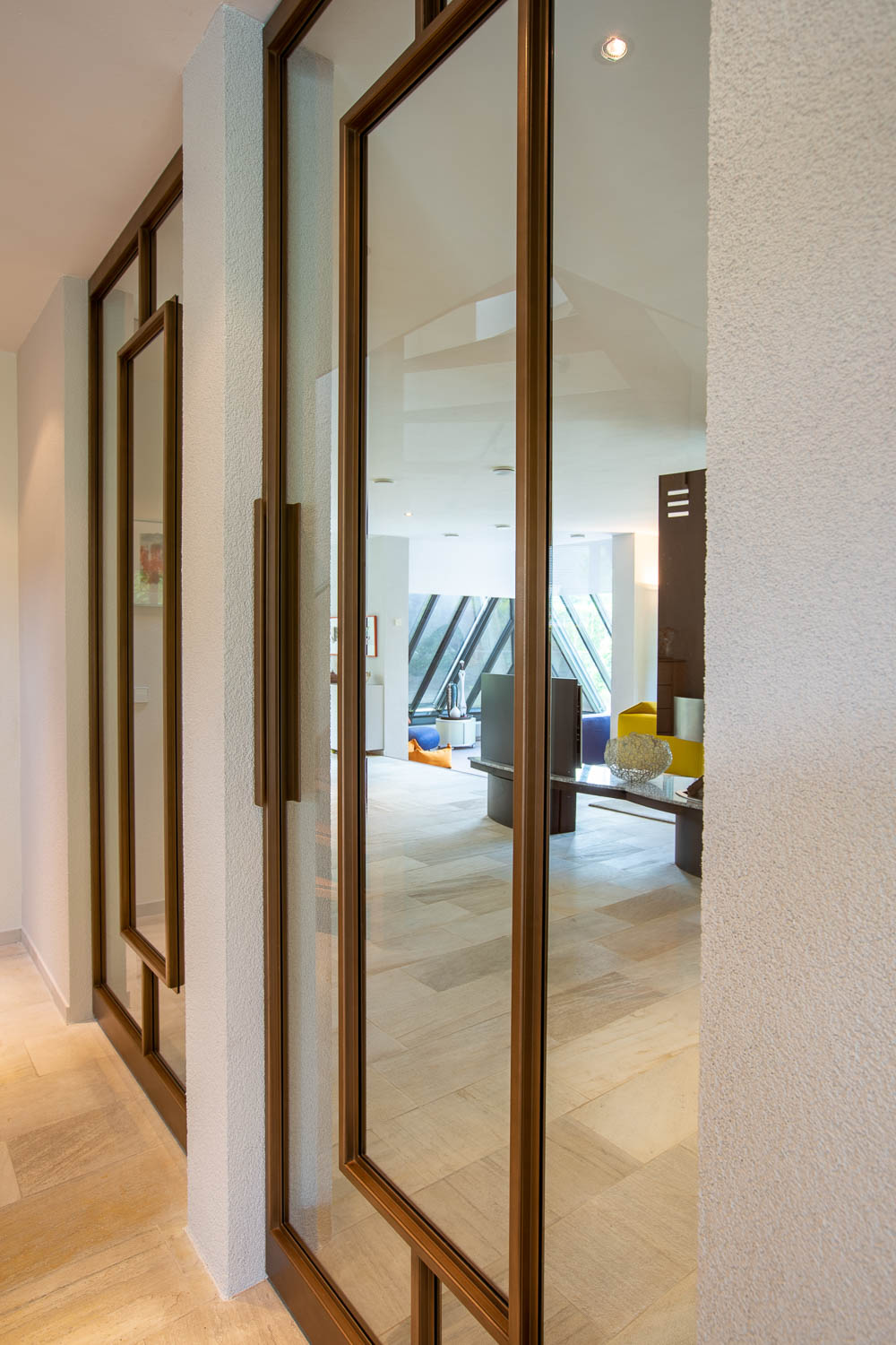 Luxe bronzen stalen taatsdeur met glas, geplaatst in een modern interieur met natuurlijke tinten.