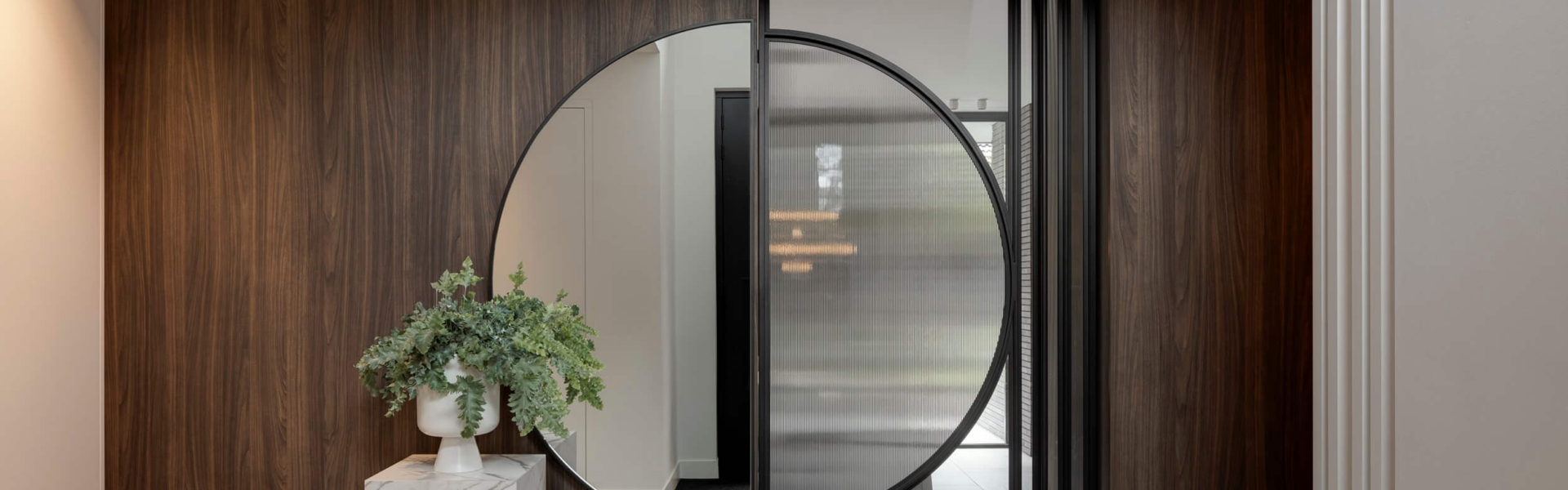 Unieke ronde stalen taatsdeur met geribbeld glas in stijlvol modern interieur.