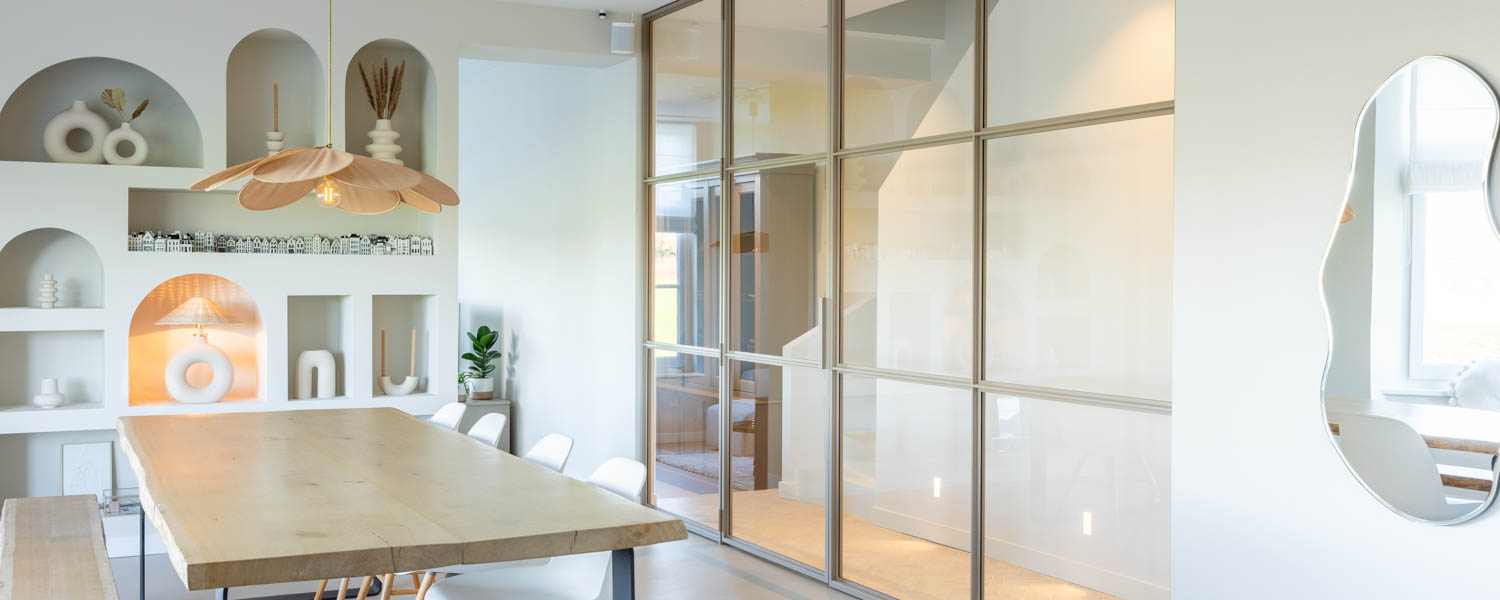 Beige stalen scharnierdeur met glas, als elegante roomdivider in een modern, licht interieur.