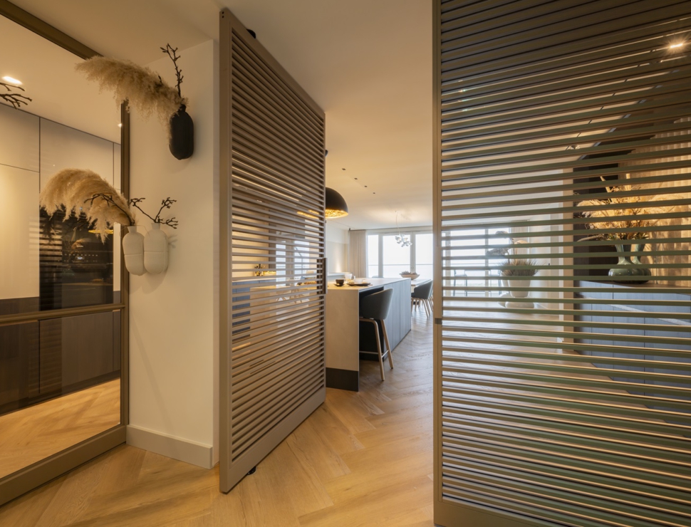 Moderne stalen roomdividers met horizontale lamellen in een luxe interieur met open keuken.