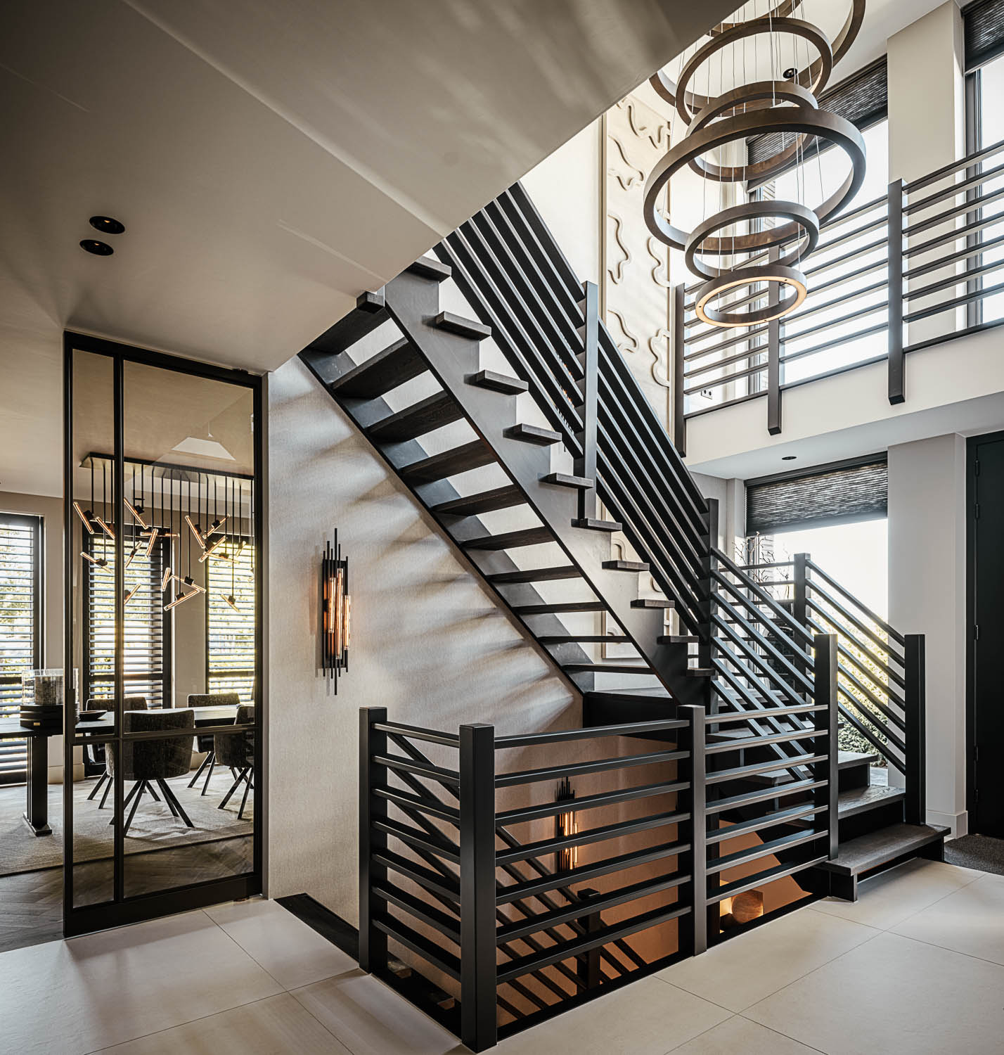 Architectonisch trappenhuis met zwarte stalen balustrade, open treden en grote designlampen.