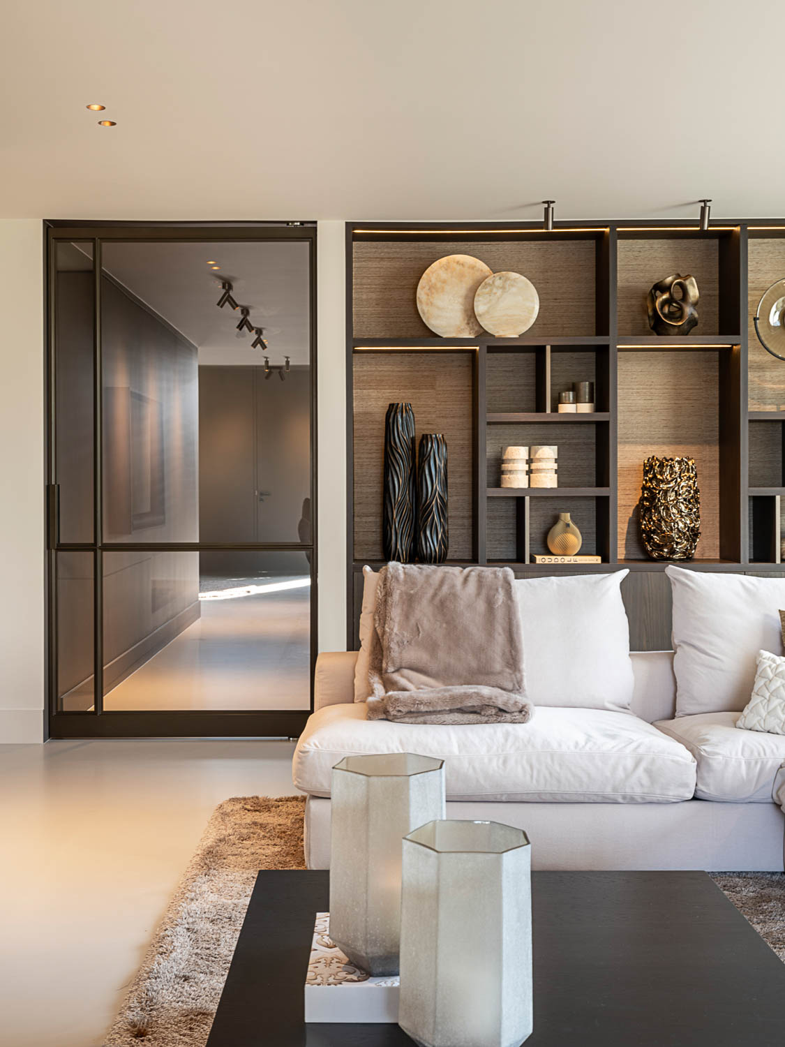 Luxe woonkamer met stalen taatsdeur in Anodic Brown, maatwerkkast en modern interieurdesign.