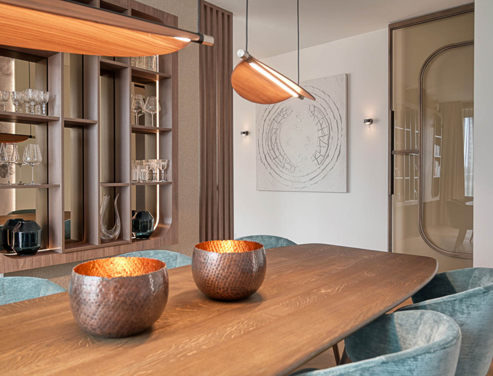 Elegante bronzen stalen deur in moderne eetkamer met houten tafel en designverlichting.