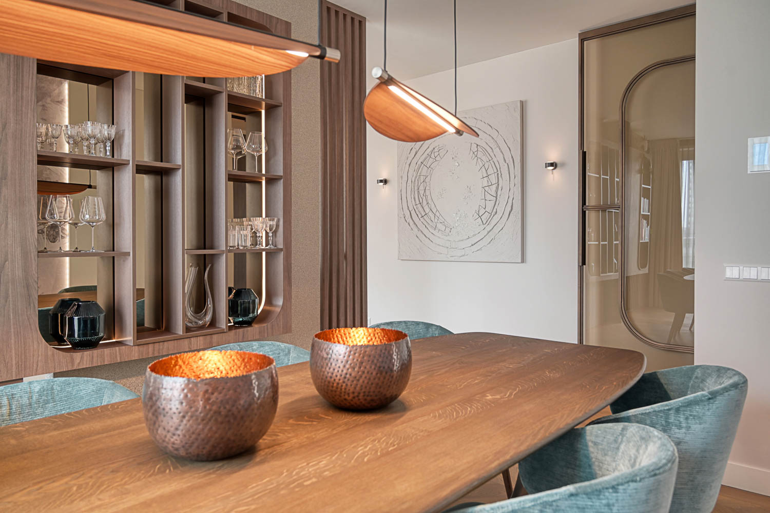 Elegante bronzen stalen deur in moderne eetkamer met houten tafel en designverlichting.