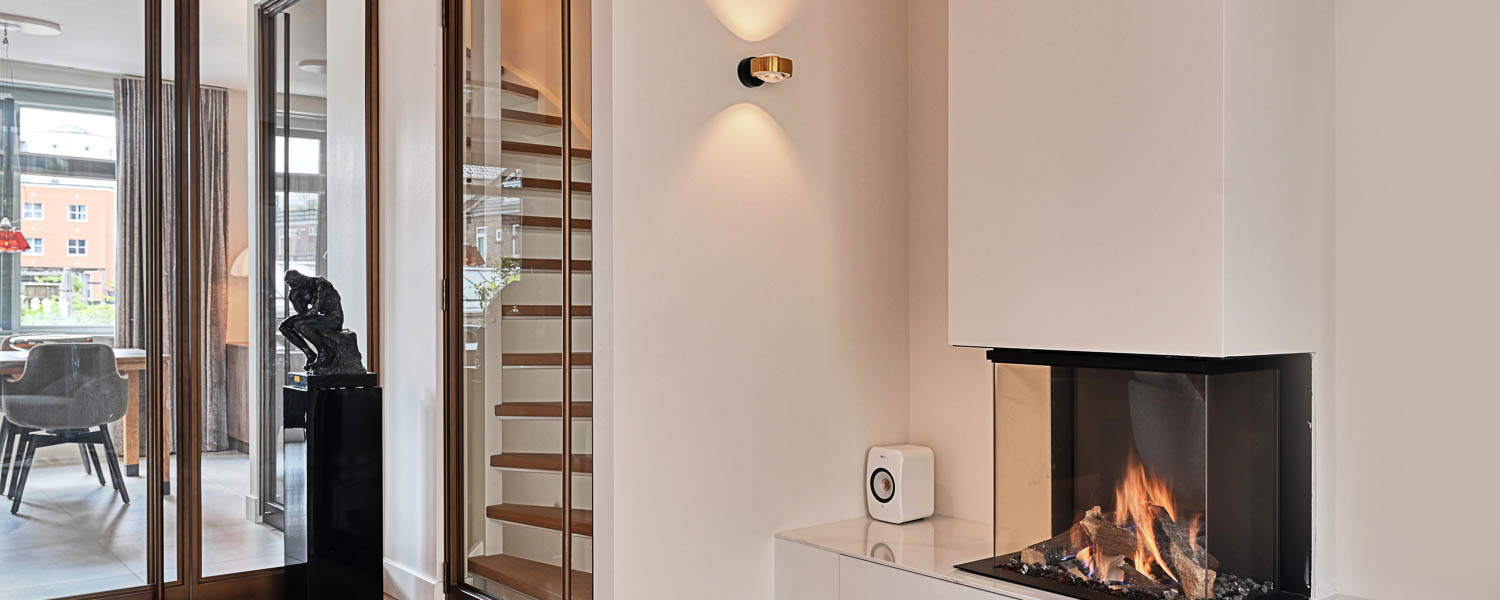 Stalen trapdeur in Royor Dark Bronze Brushed met glas, naast trap met houten treden in modern interieur.
