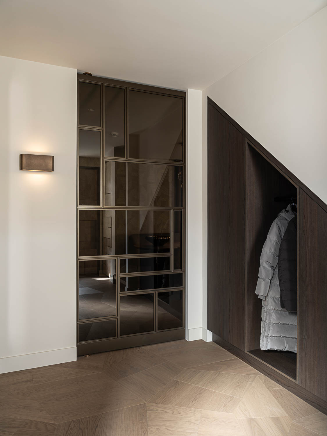 Luxe bronzen stalen taatsdeur met glas, geïntegreerd in een modern interieur met houten visgraatvloer.