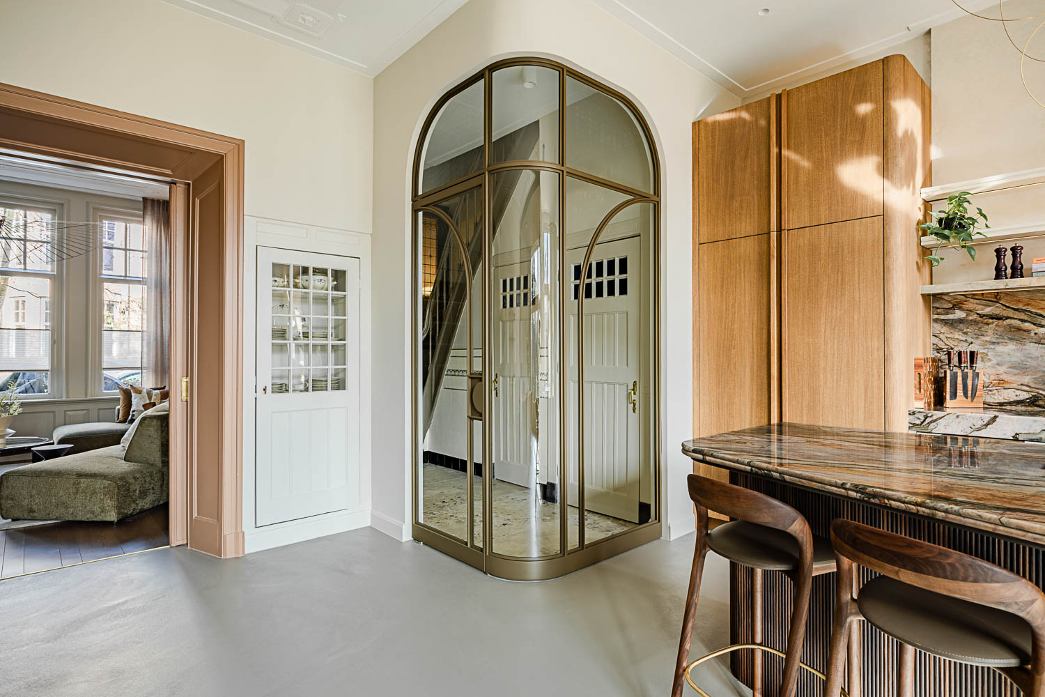 Bronzen ronde stalen deur met glas als eyecatcher tussen keuken en hal.