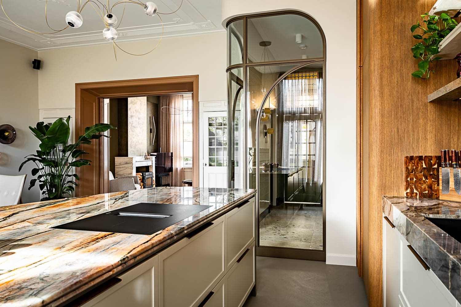 Luxe keuken met marmeren werkblad en bronzen stalen glasdeur naar hal.