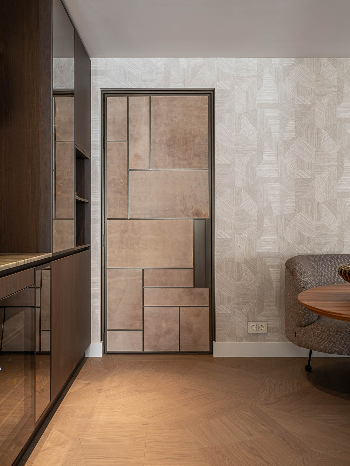 Moderne binnendeur met geometrisch patroon en suède-look panelen, omringd door een warm eigentijds interieur.