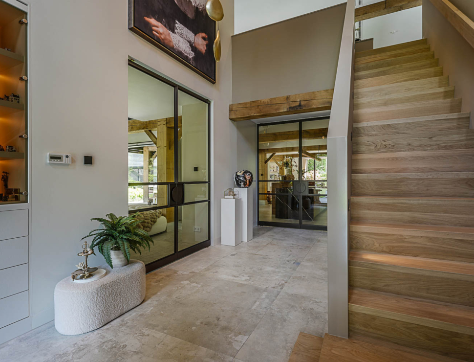 Zwarte stalen taatsdeuren met glas als stijlvolle roomdivider in luxe hal met natuurstenen vloer.