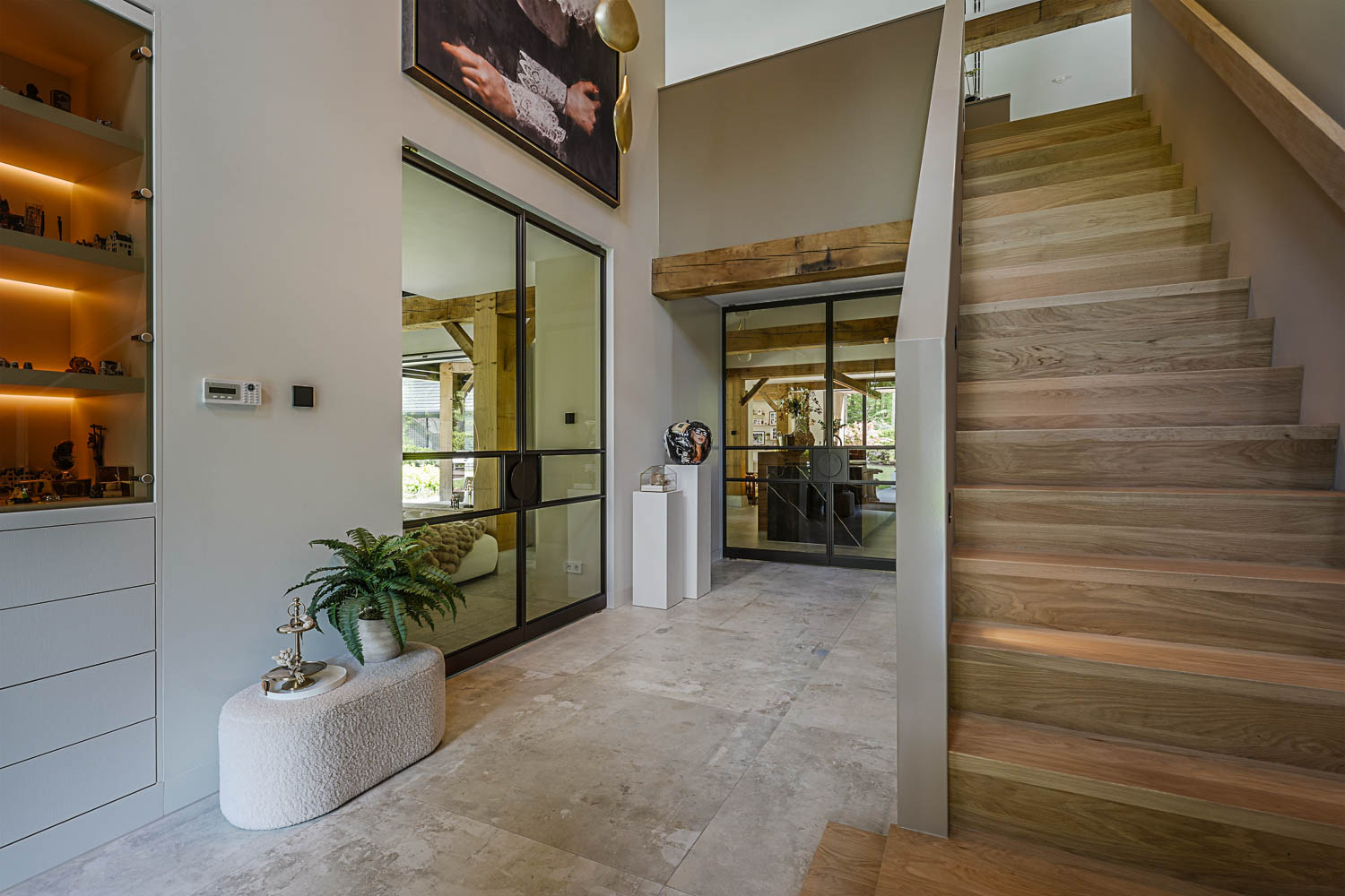 Zwarte stalen taatsdeuren met glas als stijlvolle roomdivider in luxe hal met natuurstenen vloer.