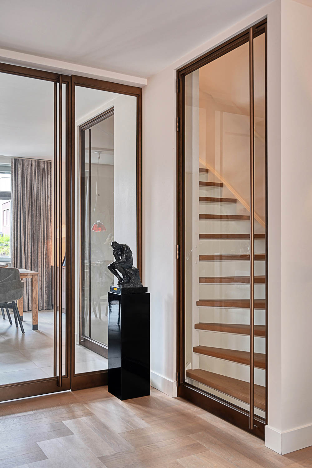 Rohe taatsdeur in Royor Dark Bronze Brushed als luxe roomdivider tussen keuken en living, met designhandgreep.
