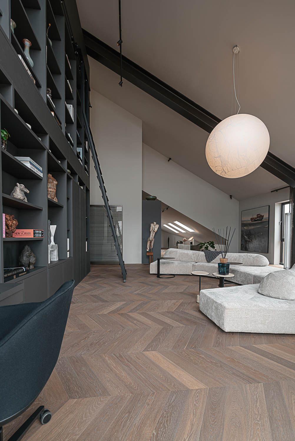 Lichte zithoek met designmeubilair en uitzicht op bronzen stalen deur met horizontale belijning.