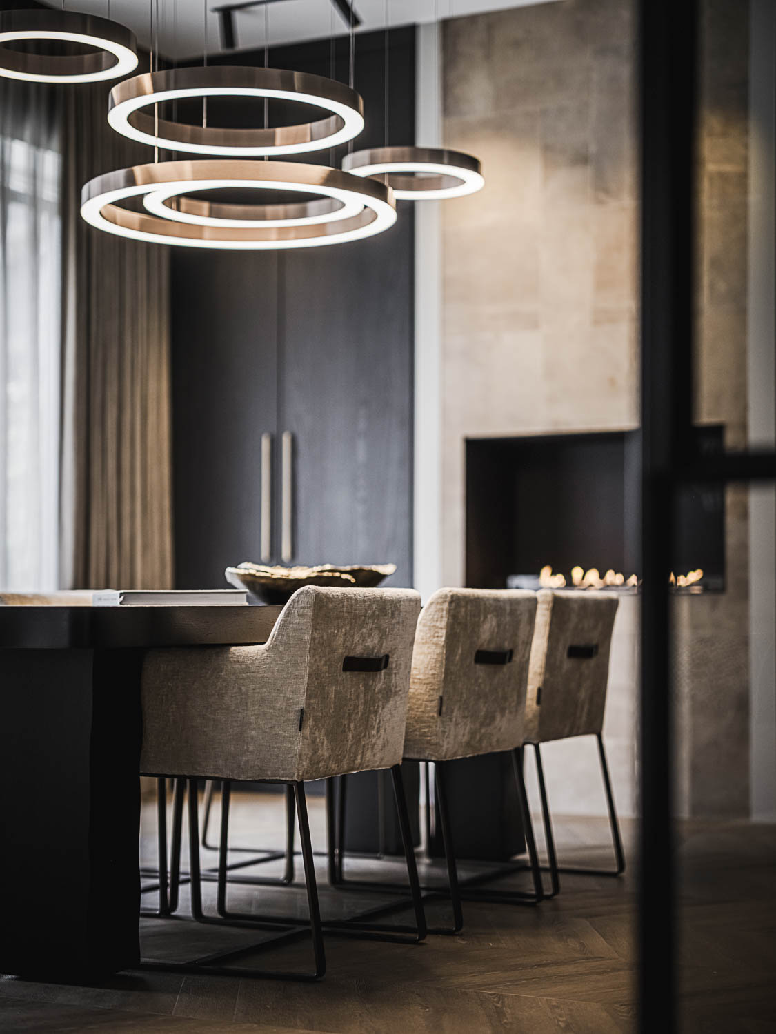 Design eetruimte met stalen deur, zwarte eettafel en ronde LED hanglampen.