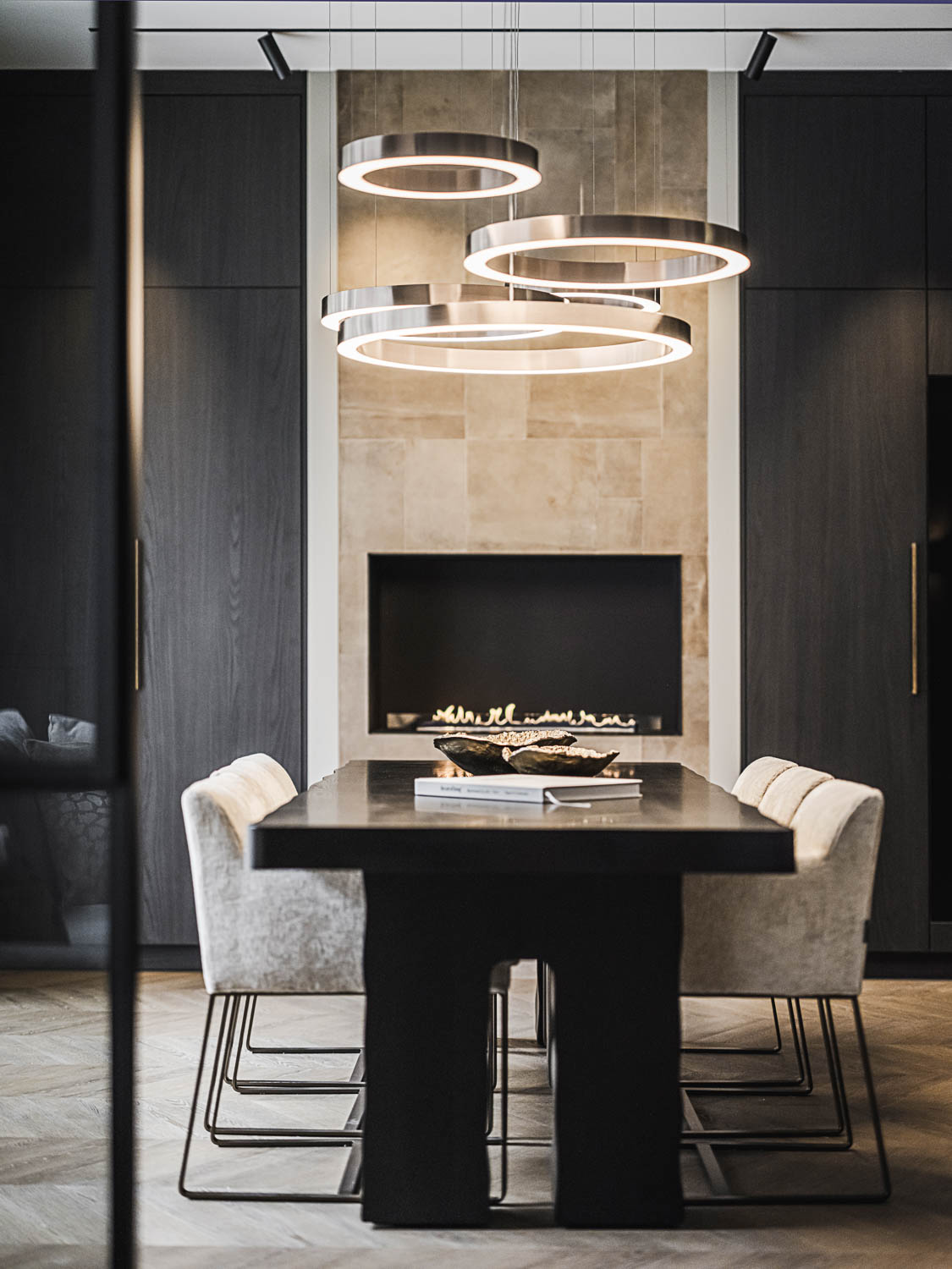 Luxe eetkamer met zwarte stalen deur, donkere eettafel en moderne haard.