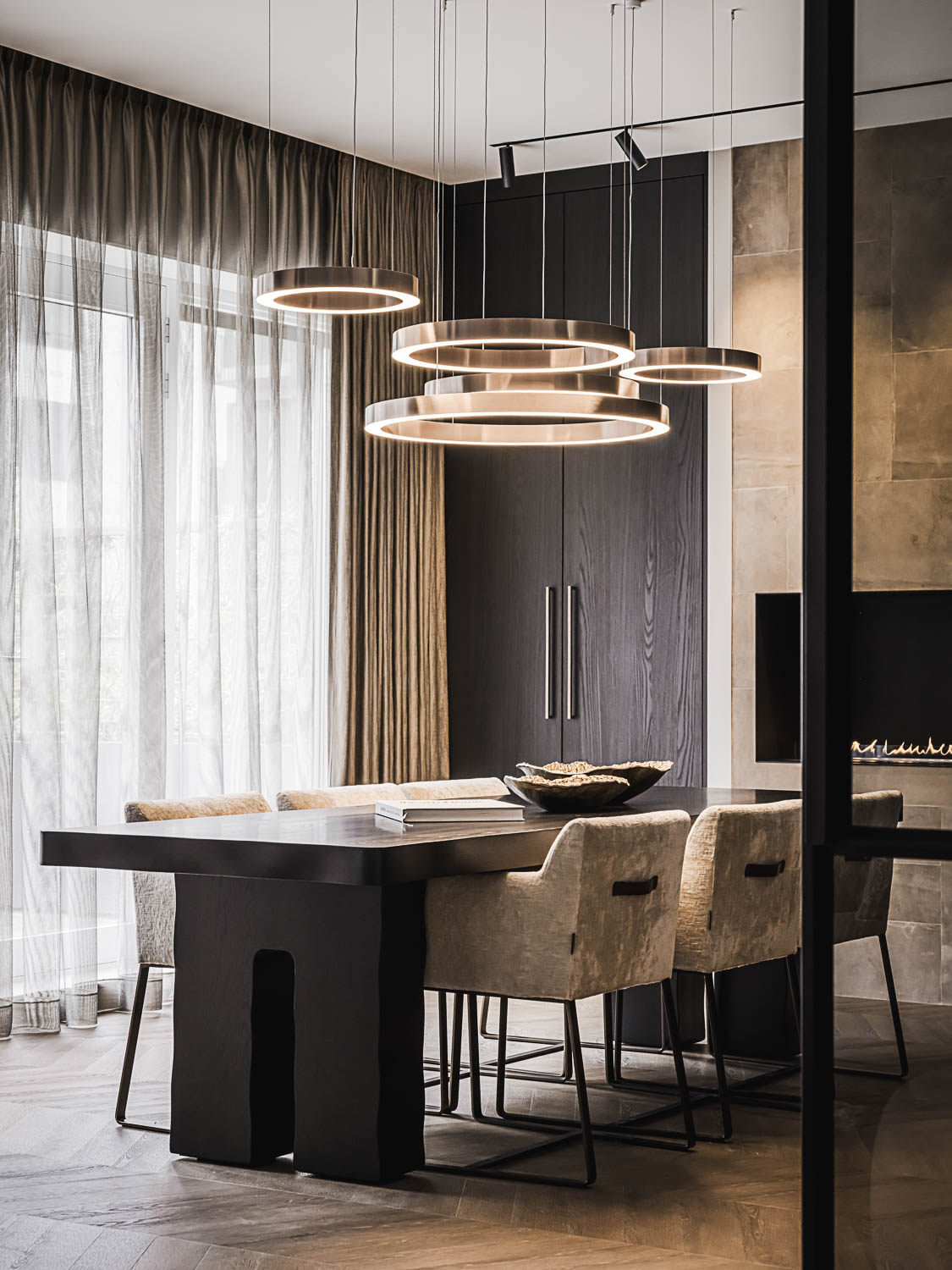 Eetruimte met stalen deur, massieve zwarte tafel en design LED verlichting.